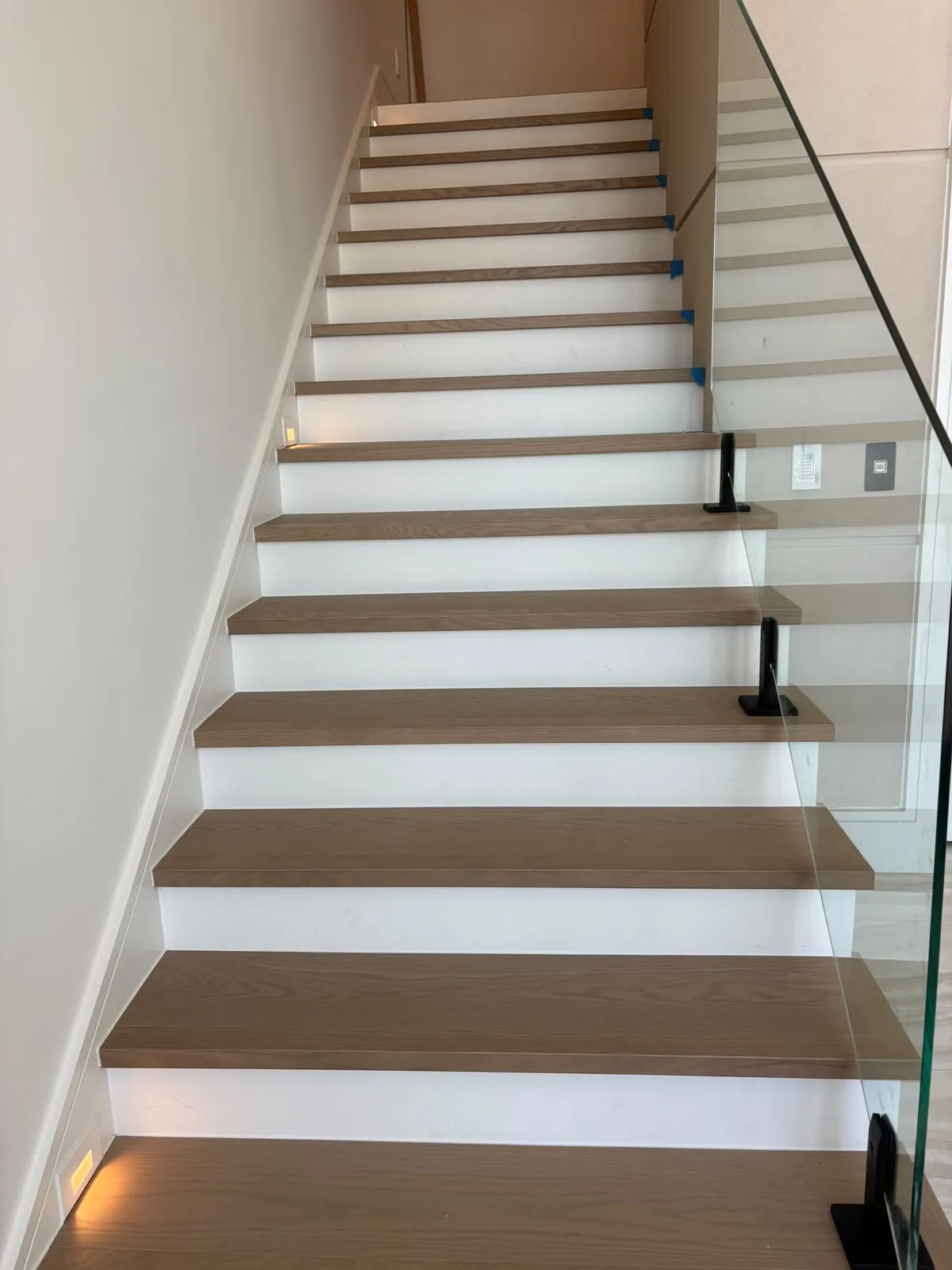 Stairs with white oak treads, white risers, and a glass railing