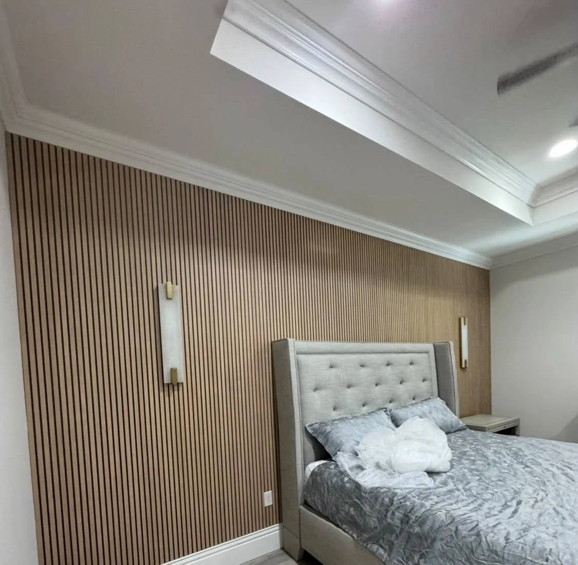 Bedroom wall covered in wood slat panels with wall lights
