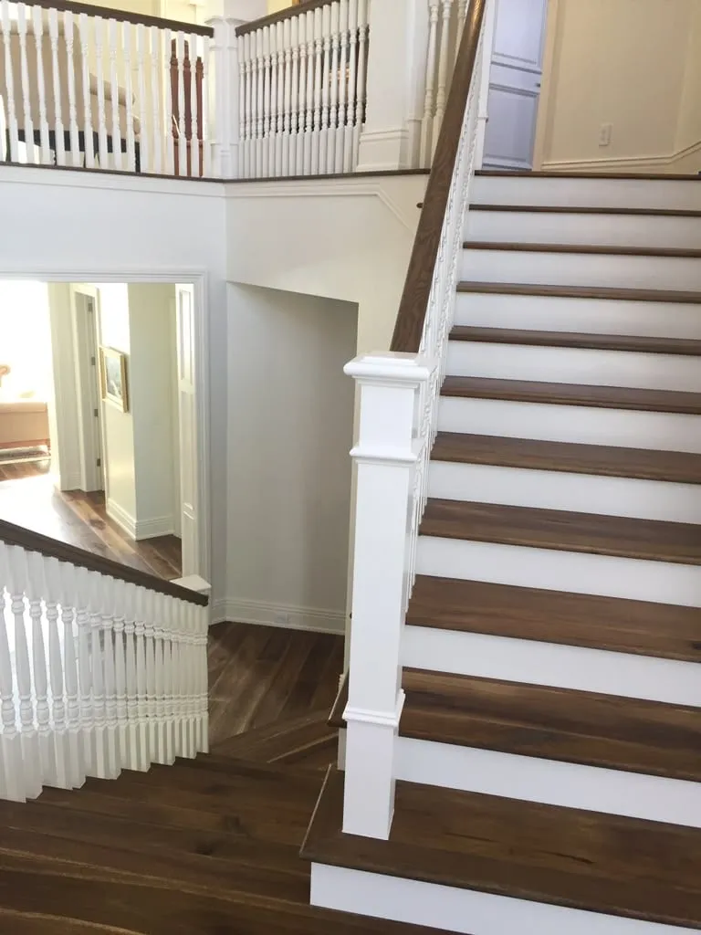 Staircase with dark wood treads, white risers, and white spindle railings