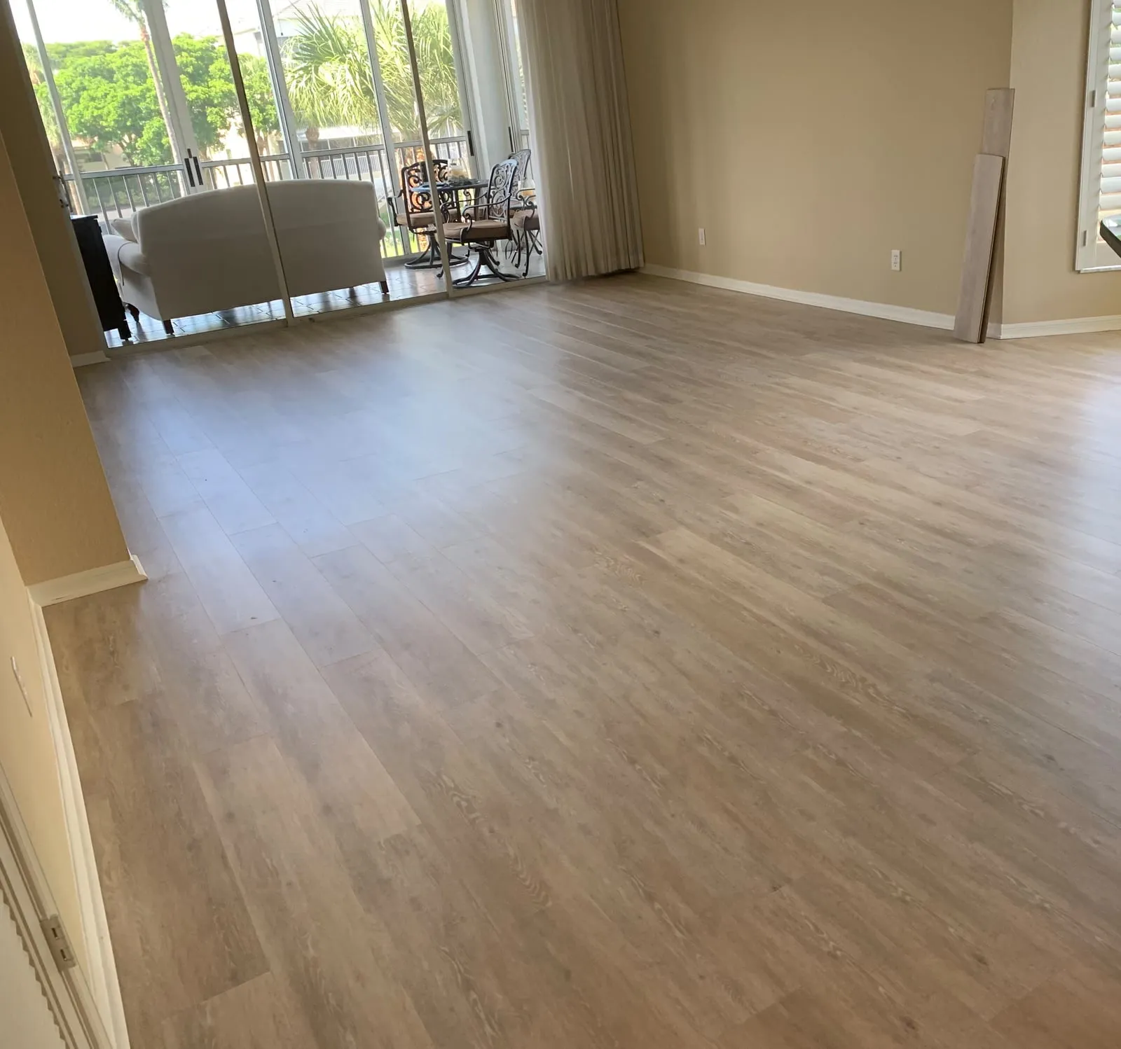 Light hardwood floor in a living room that opens to a screened lanai